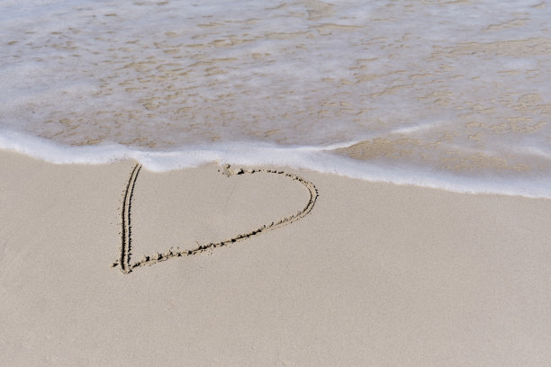 在热带海滩的白色沙滩上，海浪涌向心的轮廓。图片下载