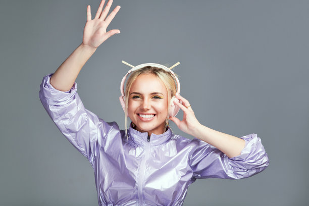 工作室拍摄的一个时髦的年轻女子戴着耳机，背景是灰色的图片下载