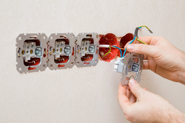 年轻的成年男子手握和安装新的墙壁插座。特写镜头。家庭维修工作。改造的过程。侧视图。图片下载