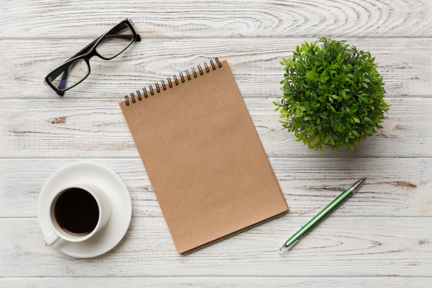现代办公桌椅，桌上备有笔记本等用品，配有咖啡杯。空白笔记本页为您设计。俯视图，平躺图片下载