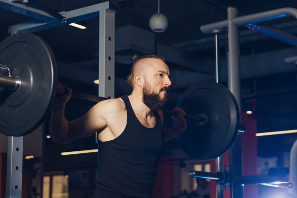 一个体格健壮的人用杠铃锻炼身体图片下载