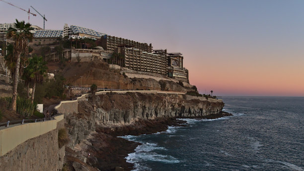傍晚，在西班牙的度假胜地波多黎各，加那利群岛，加那利群岛南部岩石海岸的美丽景色，有长廊，酒店建筑和五彩缤纷的天空。图片下载