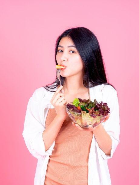 亚洲可爱的女孩感到高兴吃减肥食品新鲜的沙拉对健康在粉红色的背景-生活方式美丽的女人图片下载