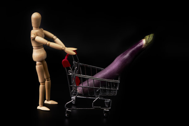 假人推着一辆黑色背景上有日本茄子的购物车。健康的购物图片下载
