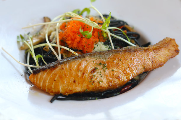 鱿鱼墨汁意大利面配烟熏三文鱼和Ebiko白盘。优雅的面。图片下载