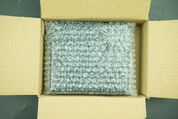 用塑料气泡把物品包裹在棕色的纸板箱里。图片下载