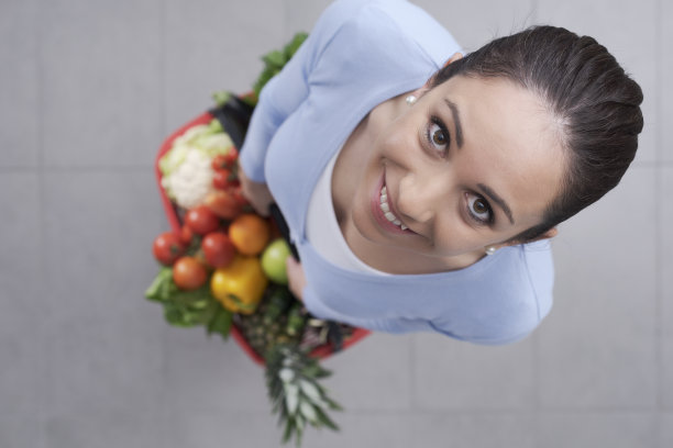 快乐的年轻女人买新鲜蔬菜图片下载