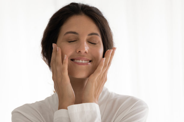 年轻美丽的女人在镜子里摸着脸的皮肤图片下载