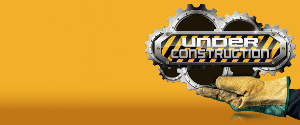 戴着手套的手拿着一个橙色背景的正在施工的标志图片下载