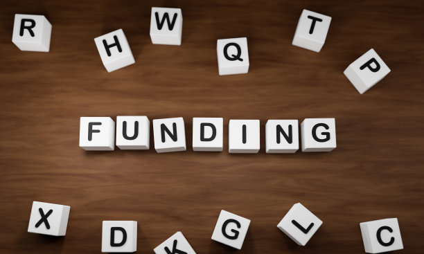 资金。白色骰子和黑色大写字母在桌子上。图片下载