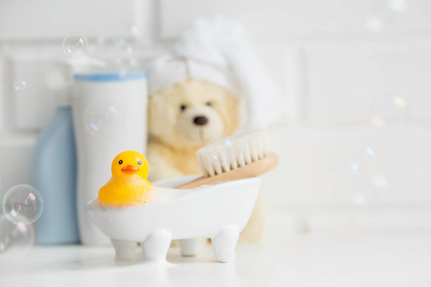 孩子的浴室配件。婴儿护理。熊头上有一条毛巾，一把刷子和几瓶洗发水。一个微型泡泡浴和一只黄色橡胶小鸭洗澡。图片下载