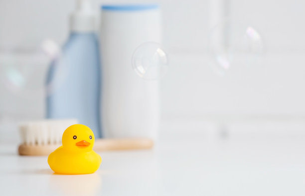 孩子的浴室配件。婴儿护理。熊头上有一条毛巾，一把刷子和几瓶洗发水。一个微型泡泡浴和一只黄色橡胶小鸭洗澡。图片下载