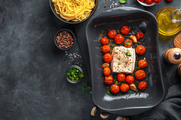 fetapasta的准备。在黑色的背景上烤羊乳酪配上番茄和香草图片下载
