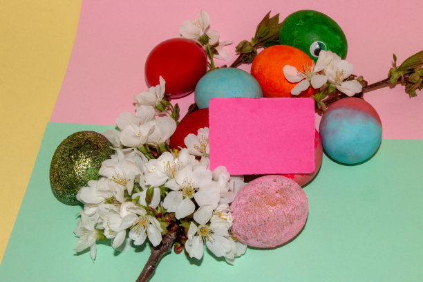 五彩缤纷的复活节彩蛋在一个小树枝上满是白色的花朵，生动的背景在花和蛋空白卡作为复制空间图片下载