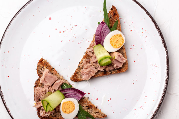 金枪鱼吐司。意大利意式意式烤面包三明治与罐头金枪鱼，黄瓜，鹌鹑蛋和洋葱在一个轻的背景，俯视图。食品配方的背景图片下载