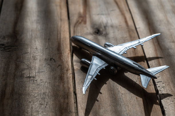 木制背景下的银色玩具飞机。粗糙、裂纹板。自然采光。图片下载