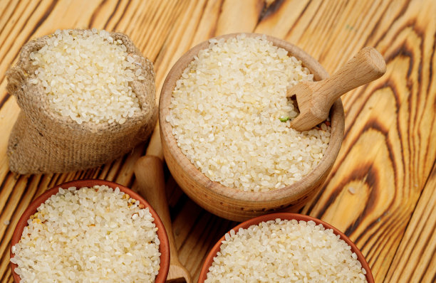 在木制的背景下，用碗和袋子装着抛光的圆米饭。高质量的照片图片下载