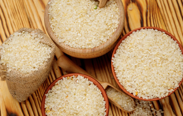 在木制的背景下，用碗和袋子装着抛光的圆米饭。高质量的照片图片下载