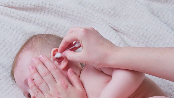 母亲用棉签清洁男婴耳朵图片下载