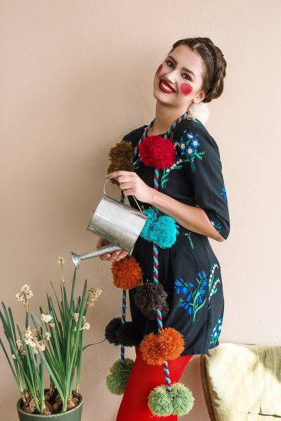 时尚美丽的黑发女孩在连体衣花卉刺绣与彩色化妆:红色的脸颊和嘴唇有乐趣，浇花。奶奶别致的风格。过肖像图片下载