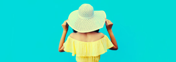 后视图漂亮的年轻女子模特摆姿势戴着夏天的草帽，穿着蓝色的背景图片下载