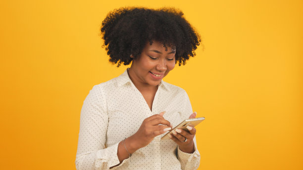 快乐迷人的非洲年轻女子跳舞孤立在黄色的背景上。开朗漂亮的女孩快乐的平板电脑笔记本网上音乐微笑和移动的身体跟着音乐积极。图片下载