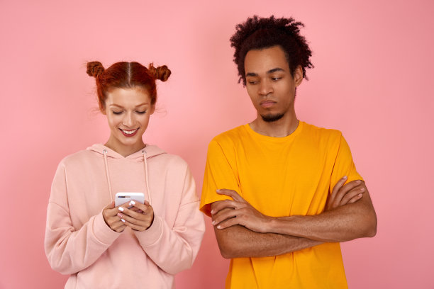 高兴的女人通过短信聊天面带微笑，无聊不满的黑人男人双手交叉图片下载