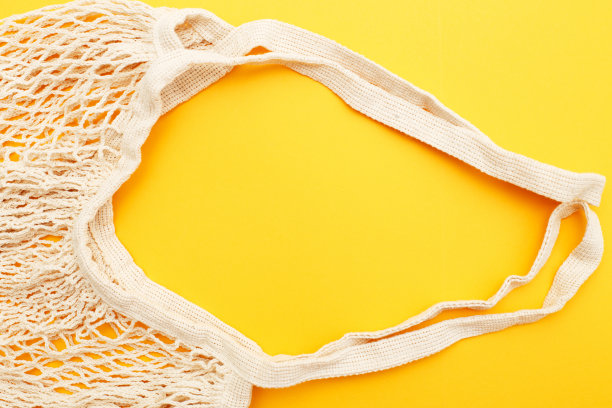 空米色可重复使用字符串购物袋在橙色的背景。塑料免费图片下载