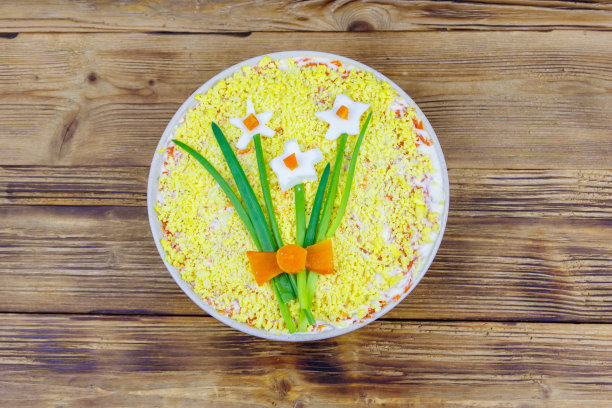 传统的俄罗斯分层沙拉含羞草与春天装饰水仙花木桌。前视图。装饰用鸡蛋、葱花和胡萝卜做成图片下载