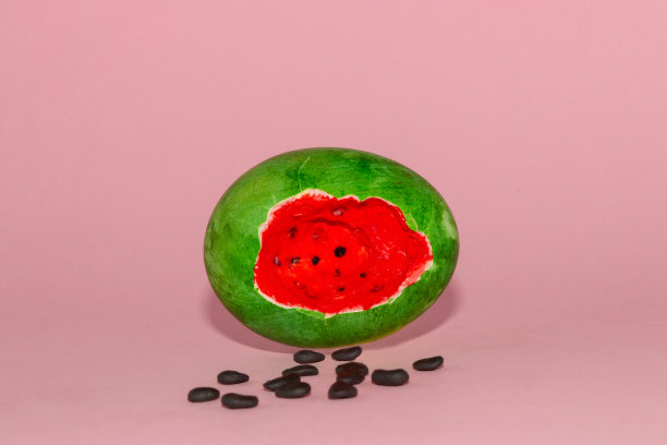 复活节彩蛋，看起来像一个西瓜和种子在一个柔和的粉红色背景，创意艺术复活节夏季设计图片下载