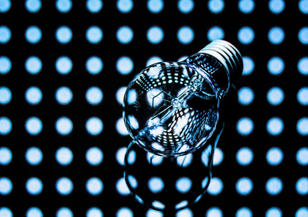 一种白炽灯灯泡，在黑暗的背景上有亮点。关于电力和照明的概念海报。图片下载