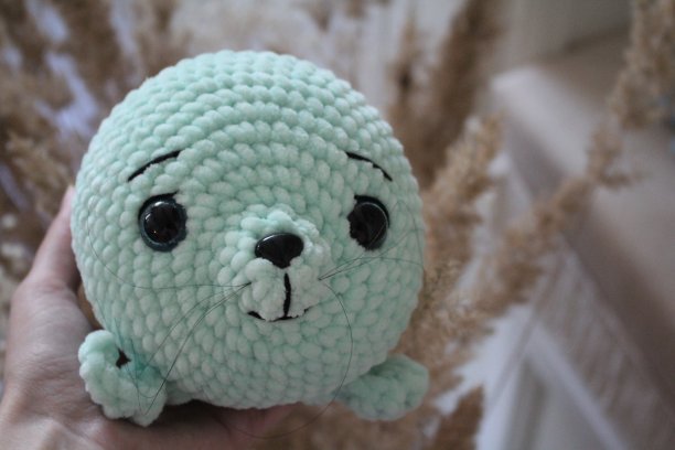 美丽可爱的针织玩具薄荷色印章在室内柔和的颜色在手上和没有手图片下载