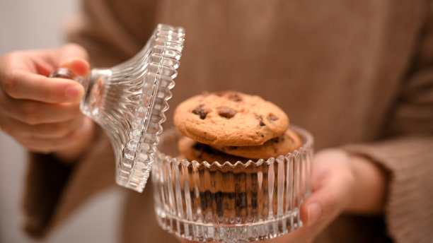 女人打开一罐巧克力饼干。甜美的糕点烘培图片下载