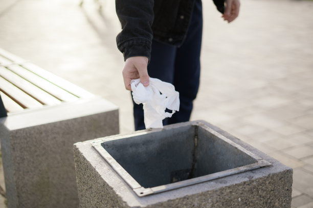 人的手把垃圾扔进垃圾桶的骨灰盒在户外的街道上图片下载