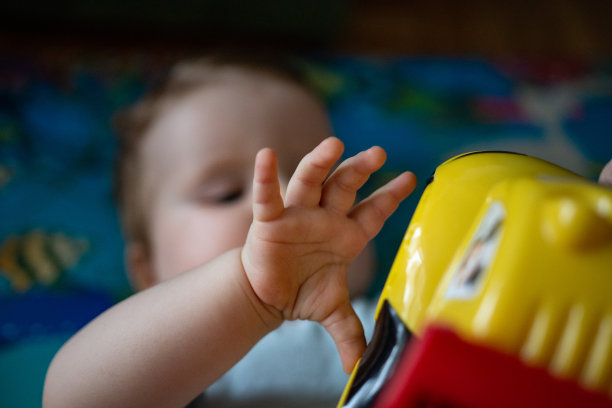 女婴躺在地板上，手里拿着玩具图片下载