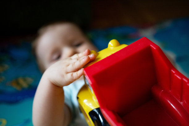 女婴躺在地板上，手里拿着玩具图片下载