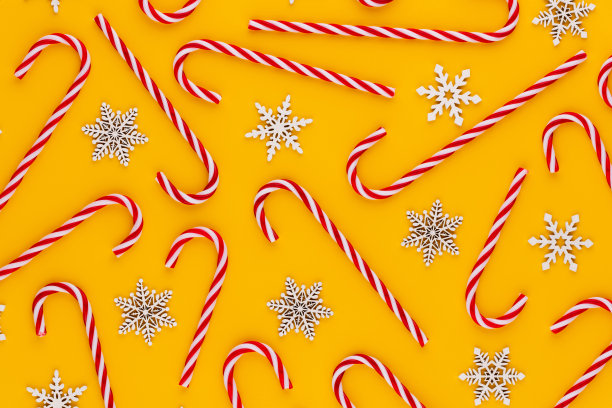 圣诞拐杖糖躺在黄色的背景上。平躺和顶视图。图片下载