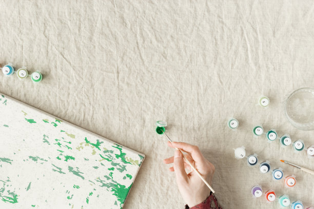 用丙烯颜料按数字绘画。女人用数字给图画上色，手拿画笔和不同颜色的颜料。创造性爱好放松，休闲活动在家里。俯视图图片下载