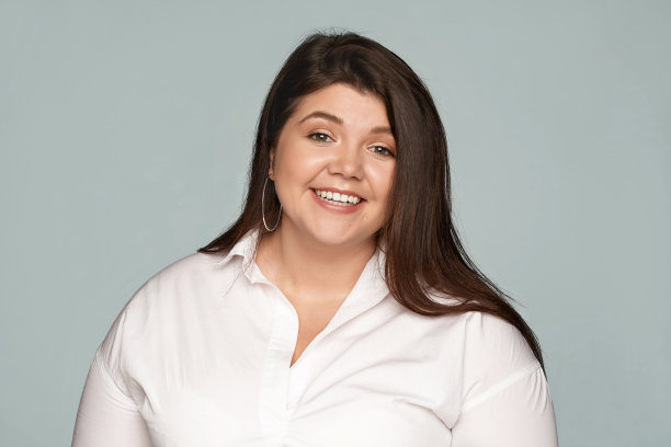 优雅迷人的年轻大码女性穿着正式的穿着，笑容灿烂，兴奋的好消息，高兴得到期待已久的升职工作。成功、工作、事业、现代生活理念图片下载