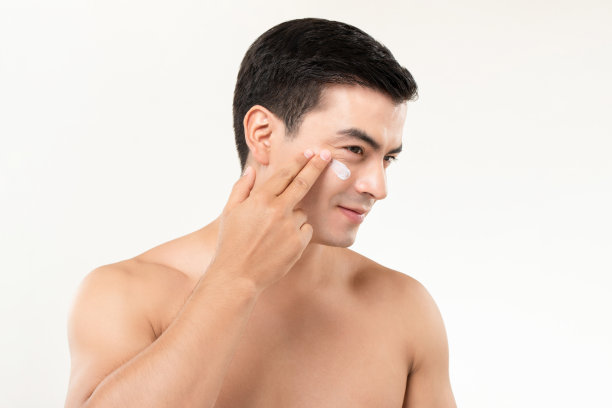 帅哥在脸上涂抹保湿霜，男士美容护肤理念图片下载
