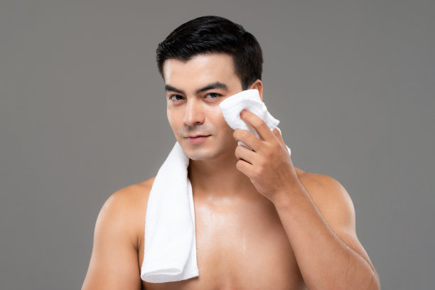 美丽和皮肤护理肖像的赤膊英俊的男子擦拭他的脸与毛巾在孤立的灰色工作室背景图片下载