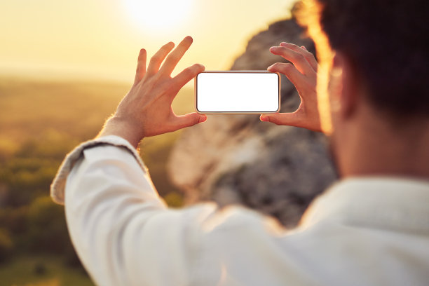 手机模型。一个年轻人在山里徒步旅行时用智能手机拍照图片下载