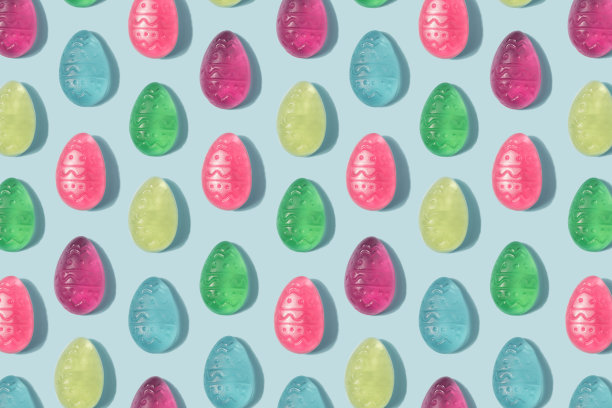 复活节彩蛋图案由彩色软糖在一个柔和的蓝色背景。图片下载