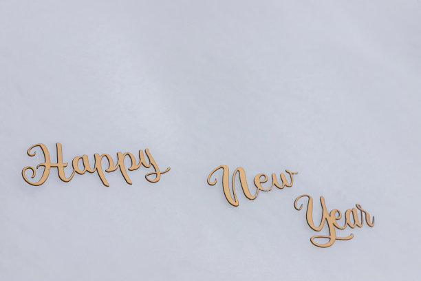 庆祝概念的金字题写在雪，新年快乐的文字在柔和的背景图片下载