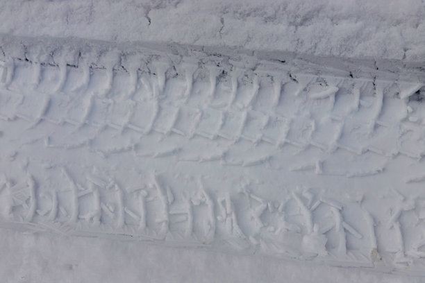 雪地里的车轮留下的冬季痕迹，特写镜头图片下载