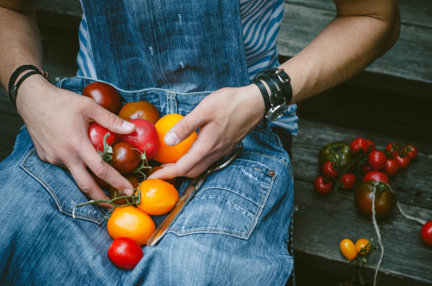 时髦时髦的现代人手里拿着新鲜美味的西红柿。牛仔裙图片下载