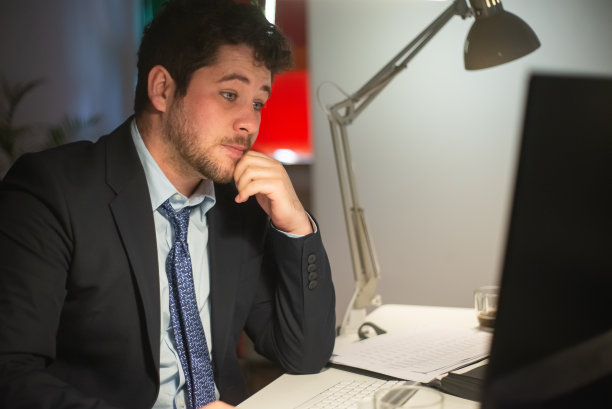 一个留着胡子的年轻人在屏幕上看书图片下载