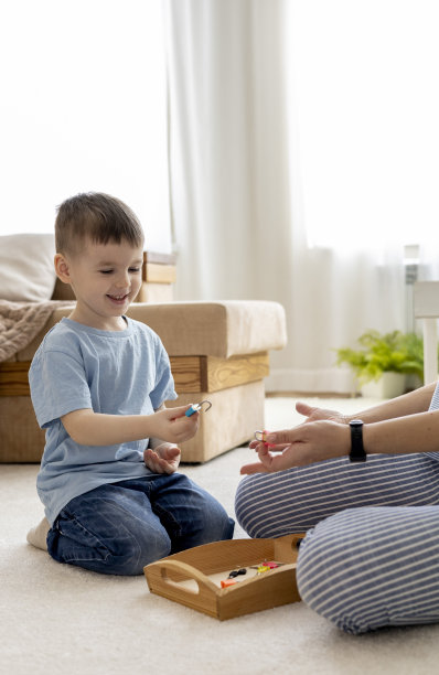 蒙特梭利的材料。一个女人和一个男孩正在用钥匙和锁研究一个谜题。图片下载