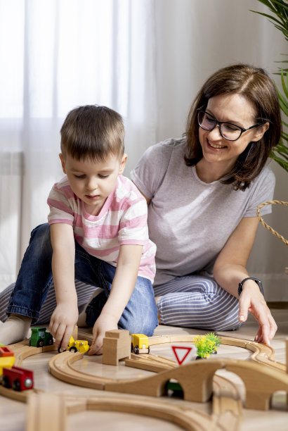 蒙特梭利的材料。妈妈和儿子通过游戏学习交通。木制的铁路。图片下载