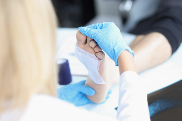 戴医用手套的医生检查病人的腿。图片下载